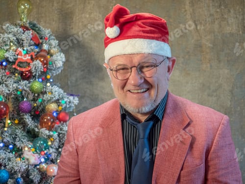 Preview: Elderly Man In Pink Jacket And Black Bandage Through One Eye, Sits On Background Of Christmas Tree