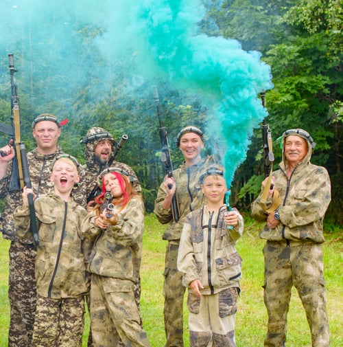 Preview: A Family In Camouflage Playing In Laser Tag Shooting Game With A Weapon Outdoor And Lights Colored