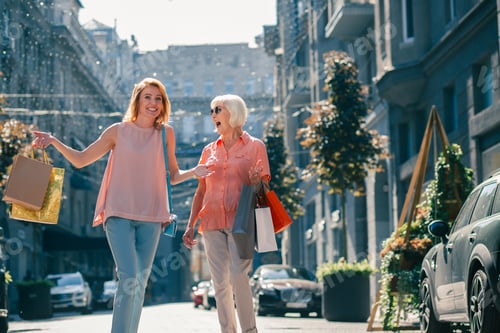 Preview: Positive Adult Lady And Her Retired Mother Enjoying Shopping Together And Laughing With Paper Bags