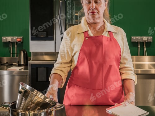 Preview: Cheerful Elderly Woman In Red Apron With Beautiful Wrinkled Face Prepares Eclairs At Master Class