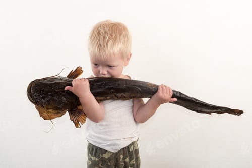 Preview: Little Boy Shows What Big Fish He Caught In River. Concept Of Organic Food.