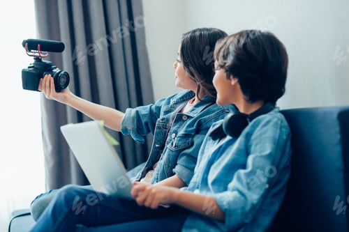 Preview: Creative Boy And Girl In Casual Clothes Sitting On A Sofa At Home. The Girl Holding A Camera With