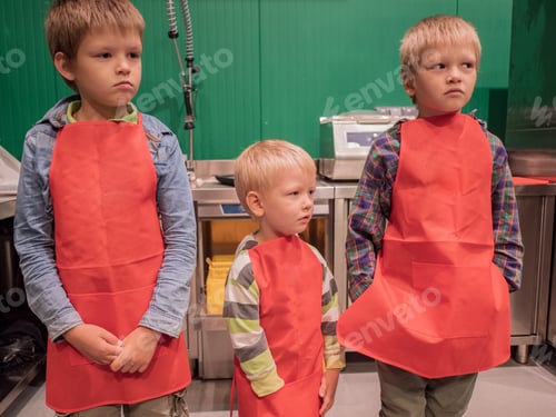 Preview: Cute Children In Red Aprons On Green Background. High-Tech Kitchen For Cooking Meat Dishes And