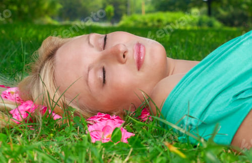Preview: Beautiful Woman Sleeping On Grass With Flower All Around Head.