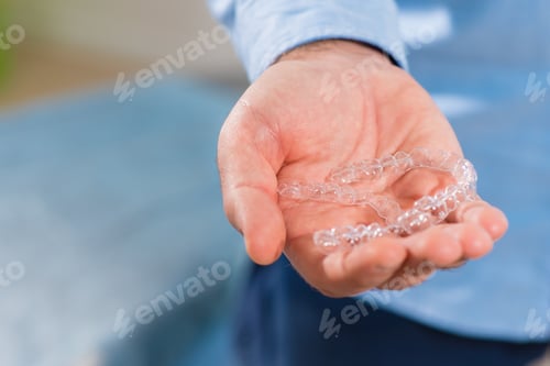 Preview: The Dentist Doctor Holds Transparent Aligners In His Hands