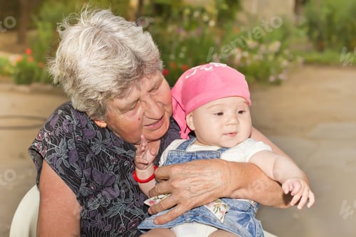 Preview: Portrait Of Smiling Senior Woman With Little Granddaughter In The Backyard.