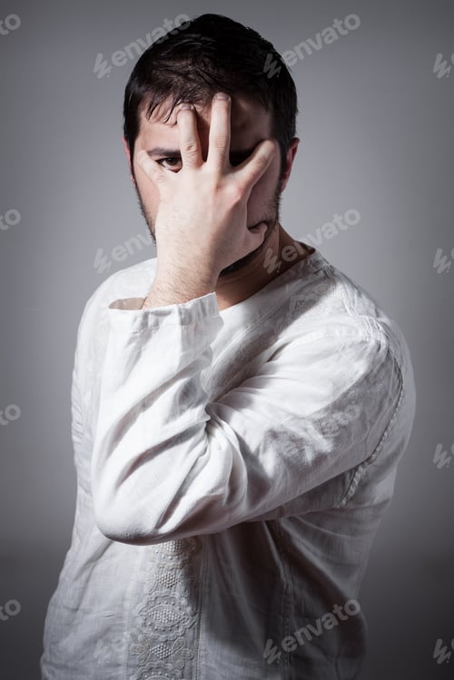 Preview: Young Man Hiding His Face With A Hand While Looking Through Fingers