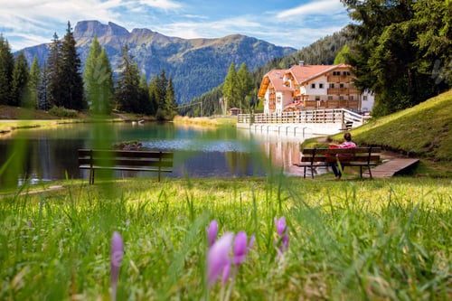 Preview: Girl Sitting On A Bench By The Lake With A Mountain View. Italian Dolomiti. Italy
