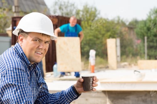 Preview: Male Engineer Holding Cup Of Coffee While Looking At The Camera At Project Site.