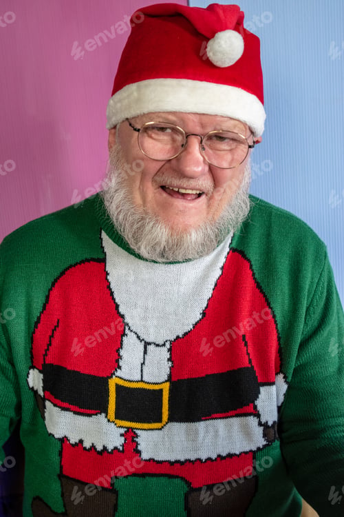 Preview: Elderly Man With Gray Beard And Glasses In Santa Claus Hat With Red Bag Filled With Presents Poses