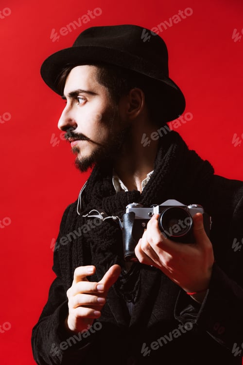 Vorschau: Kreativer Fotograf posiert im Studio mit Kamera in der Hand