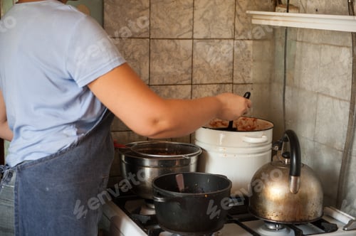 Preview: Woman Cook In Apron And Cap Cooks In Kitchen, Cuts Eggplants, Peppers, Onions, Garlic On Cutting
