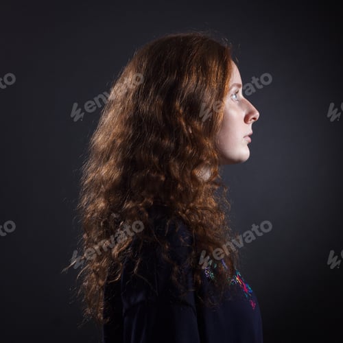Preview: Portrait Of Young Woman With Red Hair In Profile Against A Dark Background.