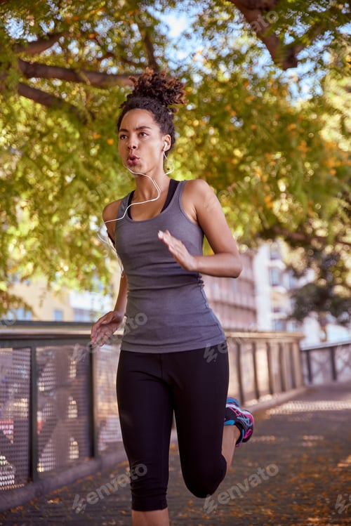 Preview: Young Woman Jogging In The Park While Listening To Music With Her Earphones And Wearing Exercising