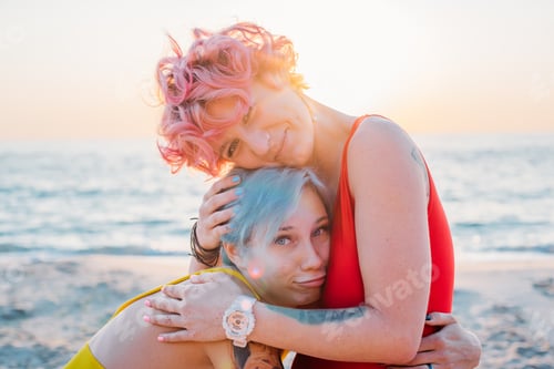 Preview: Two Beautiful Women In Red And Yellow Swimsuits Having Fun On Beach During Sunset Or Sunrise
