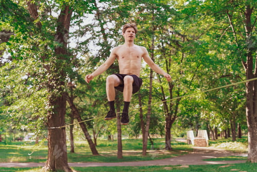 Preview: Young Man Balancing And Jumping On Slackline. Man Walking, Jumping And Balancing On Rope In Park.