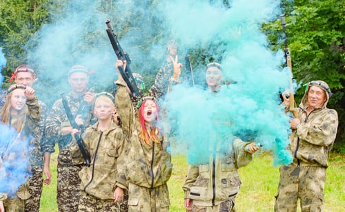 Preview: A Family In Camouflage Playing In Laser Tag Shooting Game With A Weapon Outdoor And Lights Colored
