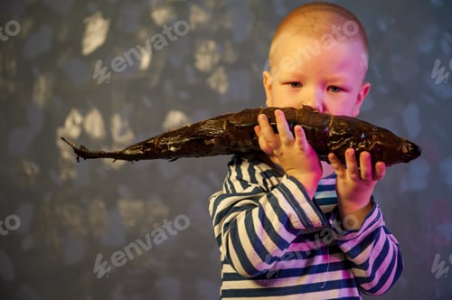 Preview: Little Blond Boy Shows Big Smoked Fish. Child Wants To Catch Big Fish In Ariver. Concept Of Organic
