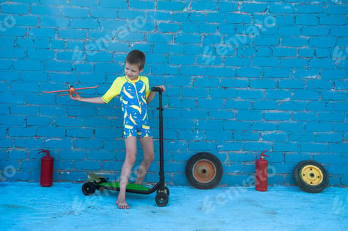 Preview: Happy Blond Child Playing With Bright Plastic Airplane Against Brick Wall In Swimsuit For Boys