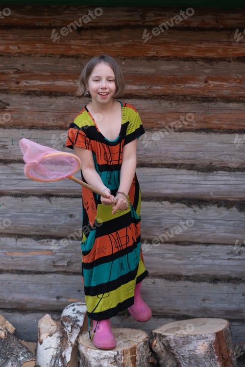 Preview: Little Country Girl Posing Near A Wooden House, Standing In A Colored Dress