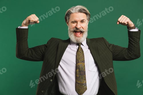 Preview: Bearded Middle-Aged Man In Khaki Suit Shows Biceps And Smiles Emotionally On Green Background