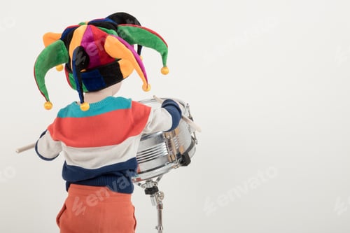 Vista previa: Happy Caucasian Child Drummer In A Carnivalous Fool'S Cap Plays On A New Drum Set. Parents Bought