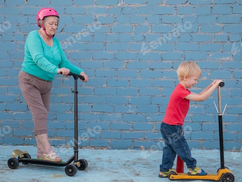 Preview: Elderly Grandmother In Turquoise Sweater Is Riding Scooter With Pretty Blond Grandson. Grandmother