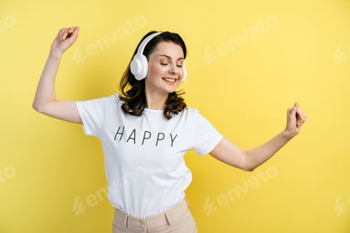 Preview: Attractive Brunette Having Fun Isolated On A Yellow Background. She Listens To Music And Dances In