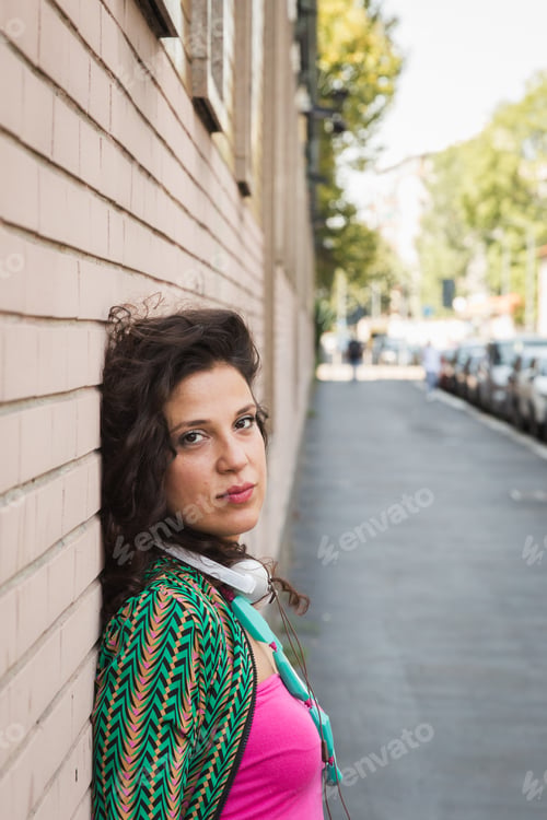 Preview: Portrait Of A Young Beautiful Brunette With Headphones Posing In The City Streets