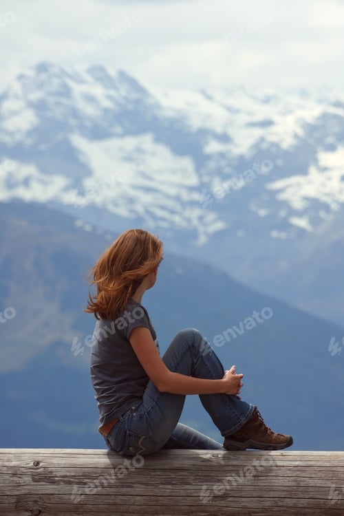 Preview: Girl Hiker Sitting And Looking At The Snowed Mountains