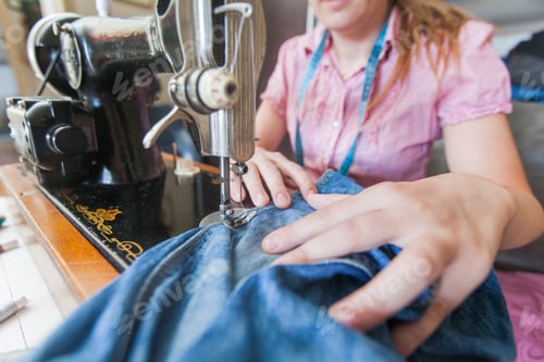 Preview: Homemaker Repairing Blue Jeans With Retro Vintage Sewing Machine At Home