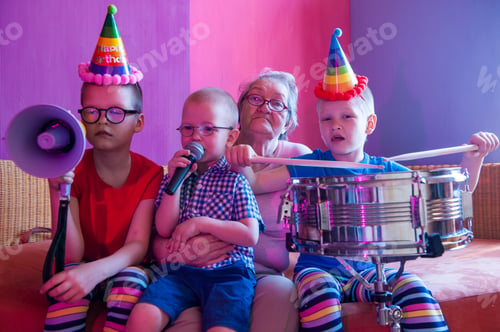 Preview: Elderly Woman In Pink T-Shirt And Glasses Holding Megaphone. Next To Grandmother, Grandchildren In