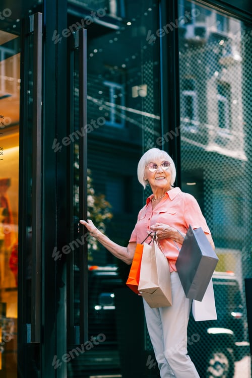 Preview: Cheerful Aged Woman Smiling While Having Paper Bags After Going Shopping