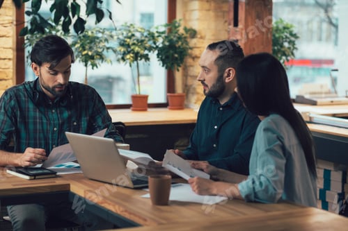 Preview: Serious Man Sitting At The Office Table And Reporting On The Company Statistics. Two Coworkers