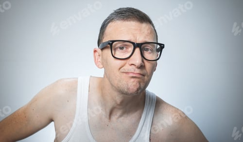 Preview: Close Up Nerd Man. Head Shot Of Funny Man Wearing Eyeglasses And Undershirt Against Gray Background