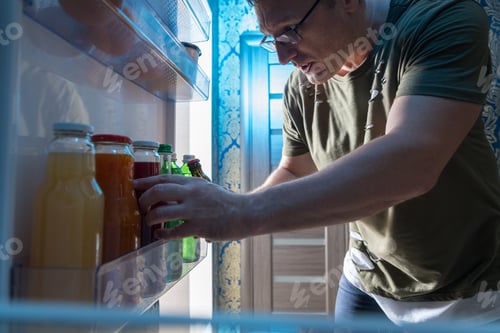 Preview: View From Inside The Fridge Of A Man Choosing A Bottle Of Fresh Fruit Juice From The Shelf On The