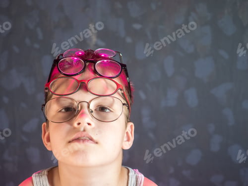 Preview: Photo Of Funny Boy, Blonde Kid With Lot Of Pairs Of Glasses On His Face. Child Is Happy At Home On