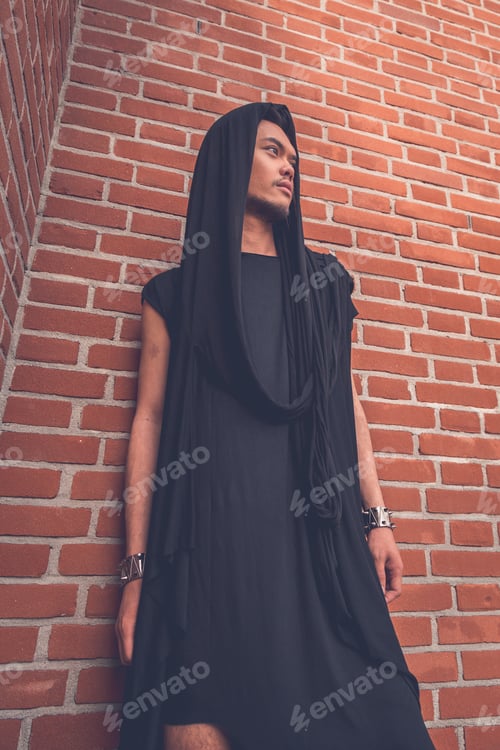 Preview: Young Handsome Asian Model Dressed In Black Tunic Posing With A Brick Wall In Background