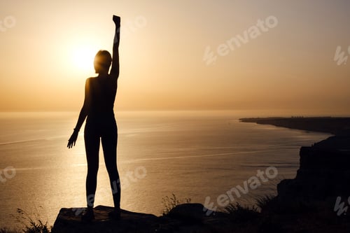 Preview: Silhouette Of Woman With Raised Hands On The Beach At Sunset. People Success, Victory, And Power