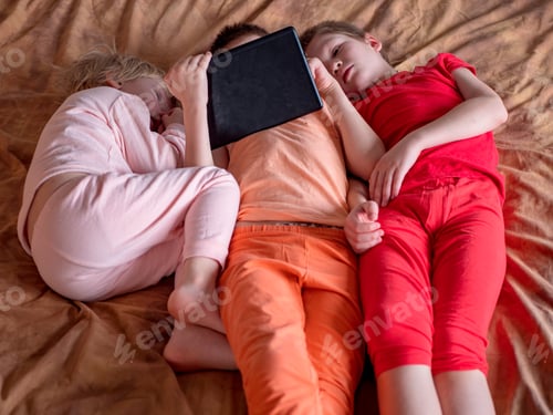 Preview: Three Boys Brothers Are Sitting On Couch And Playing Computer Game On Tablet. Children Are Happy