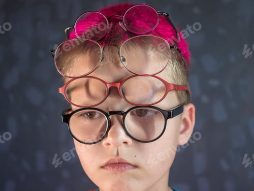 Preview: Photo Of Funny Boy, Blonde Kid With Lot Of Pairs Of Glasses On His Face. Child Is Happy At Home On