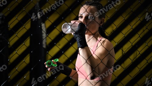 Preview: Female Fighter Drinking Water From The Bottle After Training. Selective Focus
