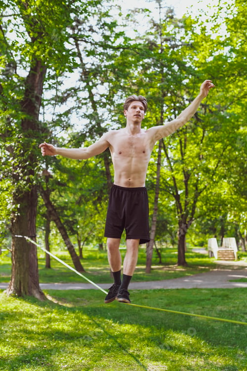 Preview: Young Man Balancing And Jumping On Slackline. Man Walking, Jumping And Balancing On Rope In Park.