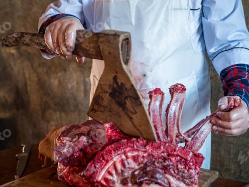 Preview: Elderly Man With A Gray Beard In Cook Suit And White Apron Cuts Into Pieces Large Piece Of Pork