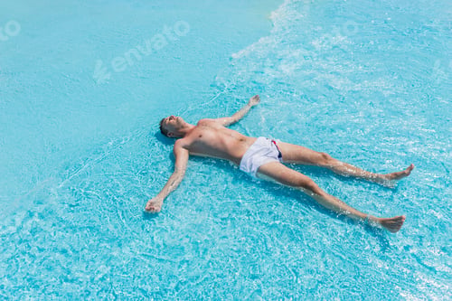 Preview: High Angle View Of Young Man Wearing Swim Trunks Lying On Back With Arms And Legs Splayed In