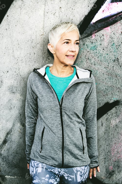Preview: Senior Woman Relax After Running, Leaning On The Gray Concrete Wall. Short Hair, Sports Clothes