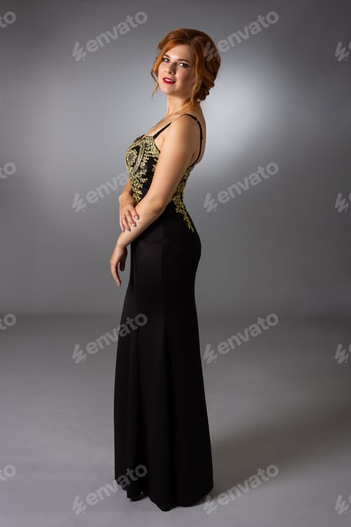 Preview: Luxurious Young Woman In A Long Black Evening Dress On A Gray Background In Full Height.