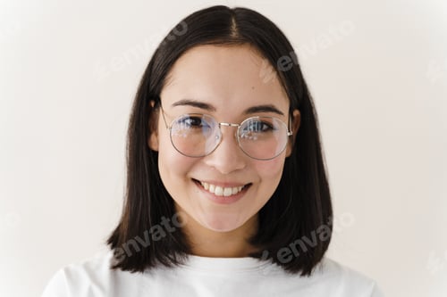 Preview: Attractive Girl With Glasses Looks Straight Into The Camera. Young Woman Posing On A White Wall