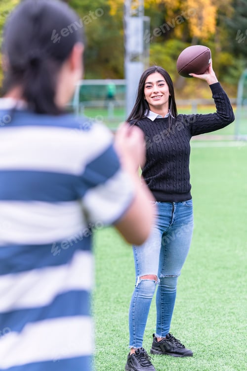Preview: Female Model Passing American Football To Her Male Friend. Couple In Park With American Football
