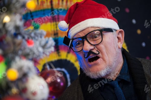 Preview: Elderly Man In Glasses With Gray Hair And Beard Next To Luminous And Blinking Christmas Lights
